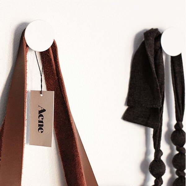 Två vita väggknoppar med en läderrem och en mörk sjal.